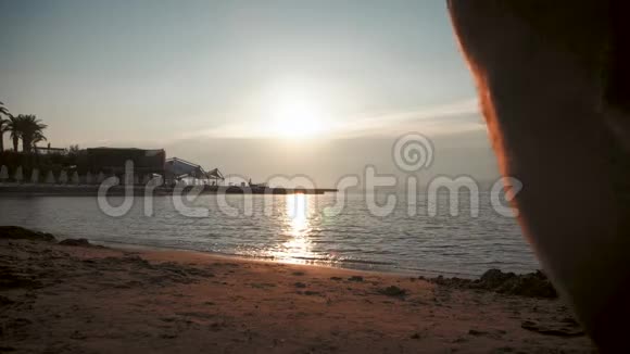 父亲和他的小女儿的剪影在日落时快乐地跑进大海溅到他们身上视频的预览图