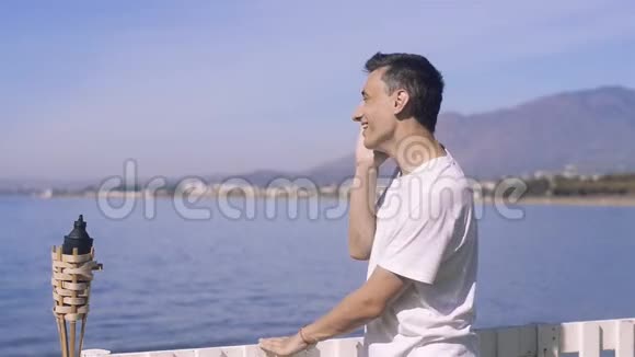 一个旅行者在大海海洋的背景上打电话微笑联系和交流的概念视频的预览图