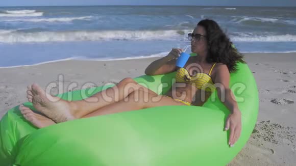 穿着比基尼的美女躺在海边充气枕头上喝鸡尾酒视频的预览图