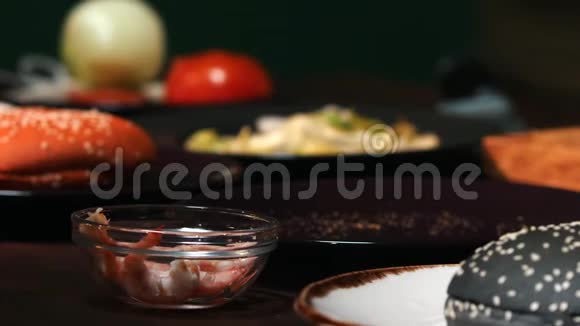 为汉堡制作提供不同配料的餐桌提供特写镜头厨师穿着蓝色围裙把几只虾放进去视频的预览图