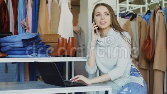 服装精品店的女老板正在用手机和笔记本电脑打字她的助手正在接近她而且视频的预览图