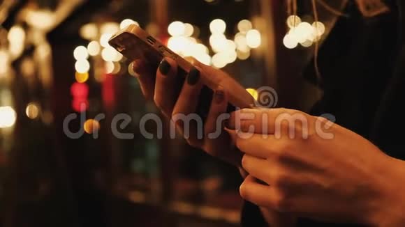 浪漫的女人在等人晚上在智能手机上上网视频的预览图