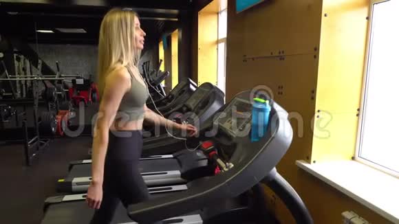 美丽的女子运动员在跑步机上缓慢运动视频的预览图