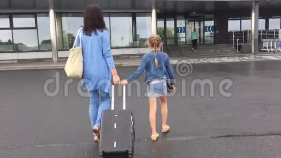 年轻的母女带着旅游套装去机场旅行箱后景视频的预览图
