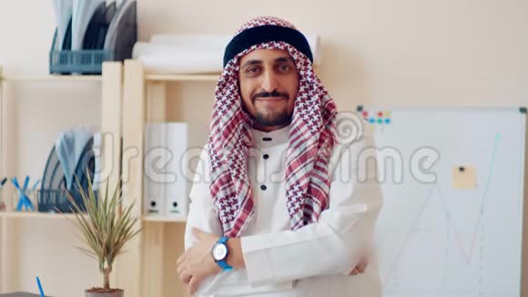英俊的年轻穆斯林男性穿着传统的伊斯兰服装站在白板上绘制的金融图表前面视频的预览图