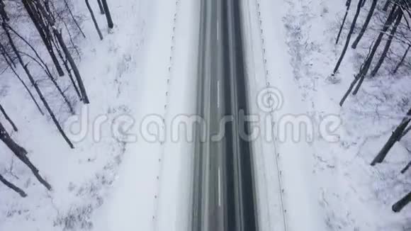在降雪的冬季森林包围的道路上卡车行驶的鸟瞰图视频的预览图