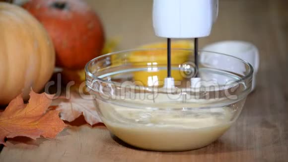 女性用手在桌子上的碗里用搅拌器搅拌面团做蛋糕做南瓜蛋糕视频的预览图