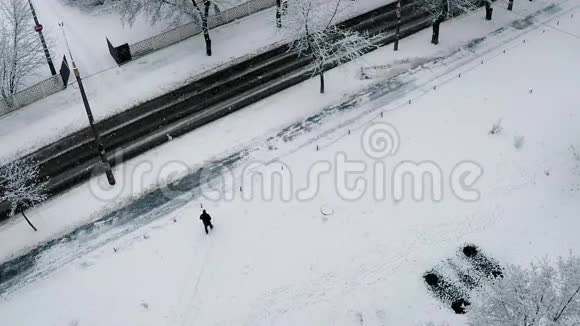 大雪纷飞的城市里大片的雪花在慢慢的盘旋从一座高楼上射出一个人正沿着马路走着视频的预览图