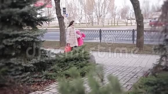 一个小女孩和她的母亲在冬天的城市里走来走去愉快地交谈着视频的预览图