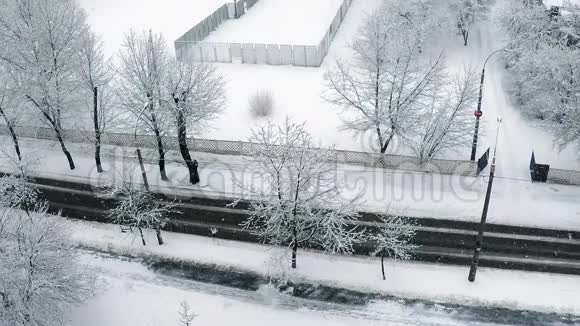 在城市里下雪从一座高楼上射出树木灯笼和一个覆盖着雪的白色栅栏视频的预览图