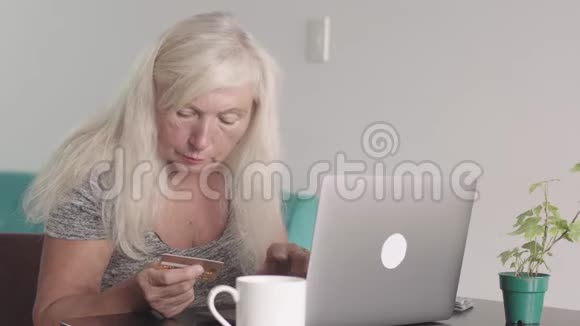 离退休老奶奶在家客厅用笔记本电脑特写镜头一位老年妇女正在购物视频的预览图