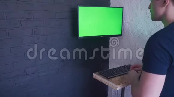 年轻人正在用一个绿色屏幕模拟电脑工作4K用两个手指在键盘上打字视频的预览图
