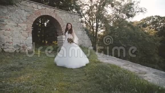 幸福的新娘手捧鲜花微笑着在古堡摆姿势视频的预览图
