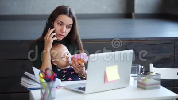 成年妇女正在用手机说话抱着婴儿跪在家里视频的预览图