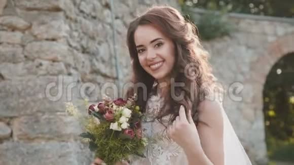 幸福的新娘手捧鲜花微笑着在古堡摆姿势视频的预览图