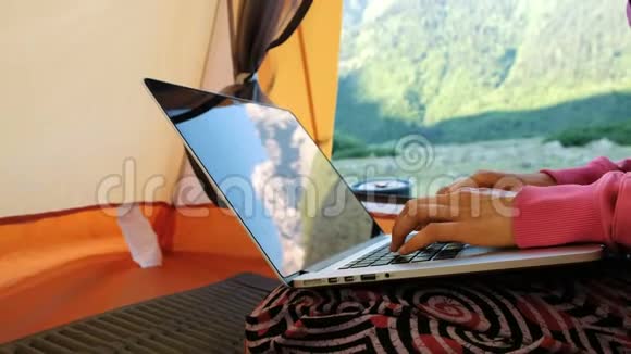山脉反映在笔记本电脑屏幕上自由职业者妇女在旅游帐篷里用电脑打字视频的预览图