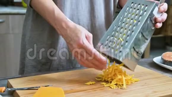 女性手的特写在金属烤架上摩擦奶酪在家庭厨房做饭视频的预览图