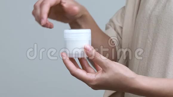 女人的特写她的手打开一个罐子白色背景上有奶油容器垂直保持视频的预览图