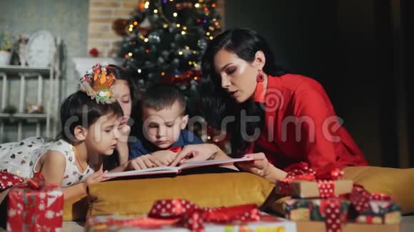 开朗的大家庭四口人正在看书新年之夜在圣诞树脚下视频的预览图