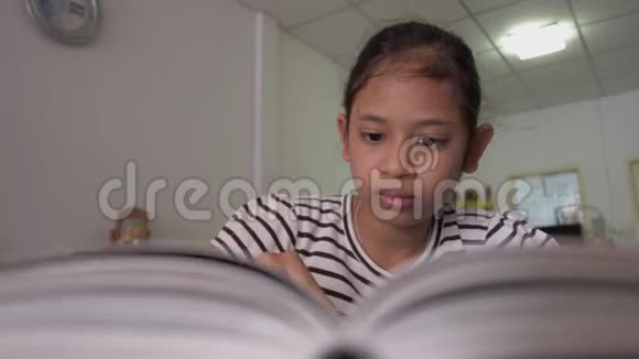 可爱的亚洲女孩在家里的桌子上读一本书视频的预览图