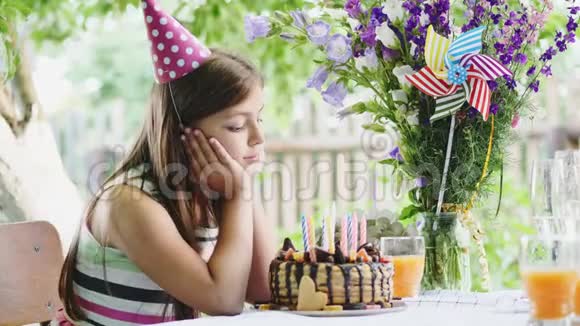 快乐的女孩坐在花园里的前欣赏一个节日蛋糕视频的预览图