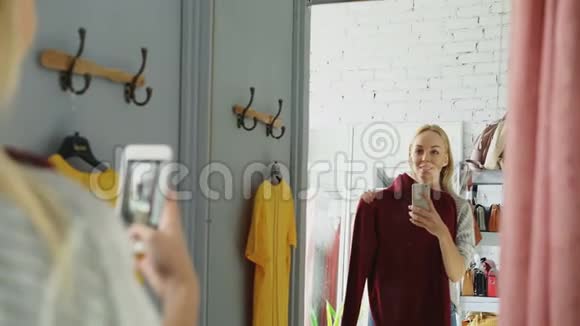 女客户正在用智能手机制作新针织跳线的镜面自拍她站在房间里视频的预览图