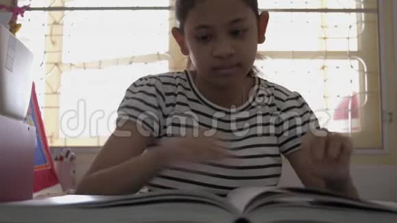 可爱的亚洲女孩在家里的桌子上读一本书视频的预览图