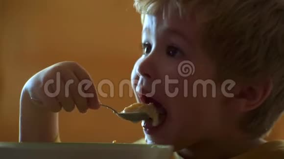饥饿的小男孩在吃东西童年孩子在家吃健康的食物微笑快乐可爱宝宝吃水果泥视频的预览图
