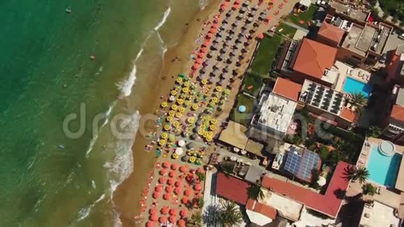 从高空俯瞰在蔚蓝的沙滩上飞翔人们在毛巾上晒太阳在绿水中嬉戏视频的预览图