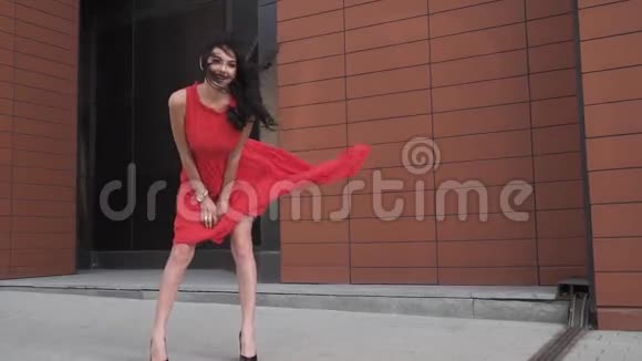 穿红色裙子的女孩微笑穿着风衣的美腿女孩风吹皱衣服慢动作视频的预览图