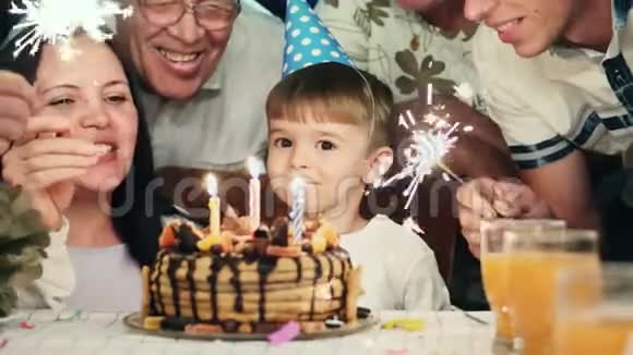 戴圆锥帽的小男孩在生日蛋糕上吹蜡烛视频的预览图