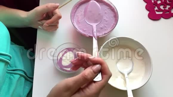 女人逐渐在容器中加入明胶甜点多种颜色的层次视频的预览图