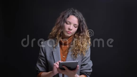 一位漂亮的女商人在平板电脑上打字看着相机微笑着的特写照片视频的预览图