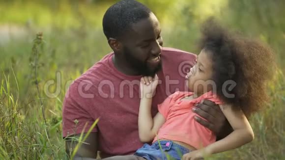 有趣的爸爸和女儿一起做傻脸坐在草地中间视频的预览图