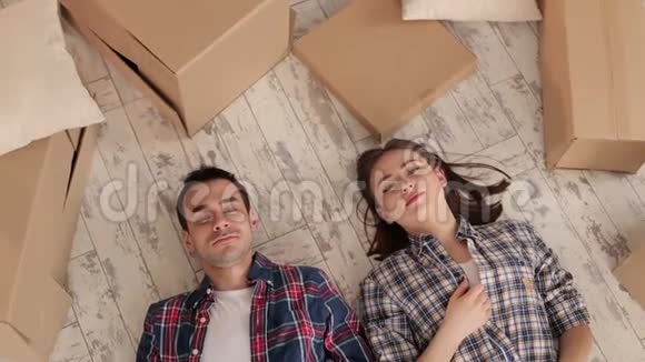 幸福的一对夫妇躺在地上手里拿着未打包的盒子视频的预览图
