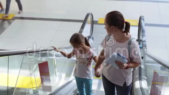 妈妈和女儿在机场的自动扶梯上站起来视频的预览图