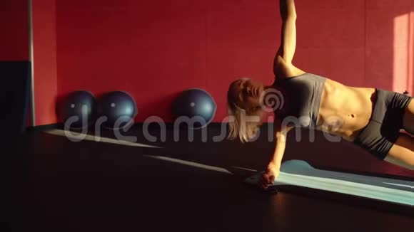 女人在蓝色垫子上做腹部锻炼的侧木板这个关于健身的视频日落光线视频的预览图