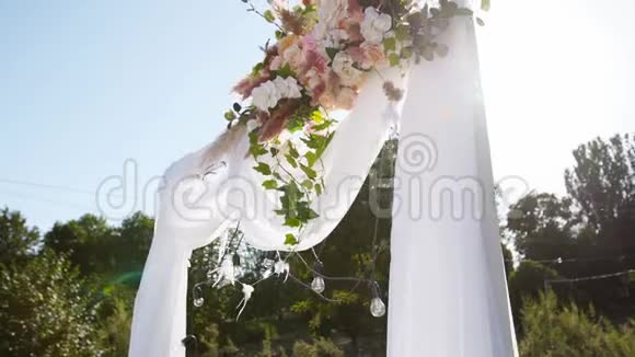 在阳光明媚的夏日婚礼拱门装饰着鲜花节日花装饰玫瑰和羽毛草视频的预览图