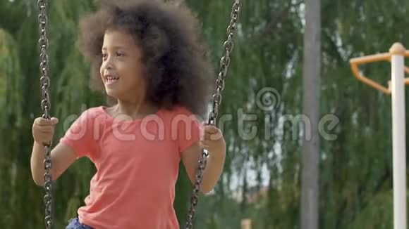 可爱的黑人女孩玩得开心在院子里上下摆动无忧无虑的童年视频的预览图