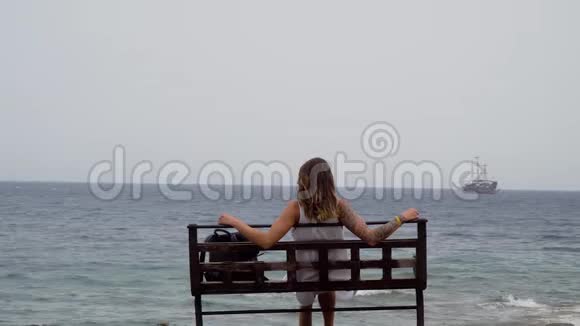 手臂上有纹身的女孩看着远处的大海视频的预览图