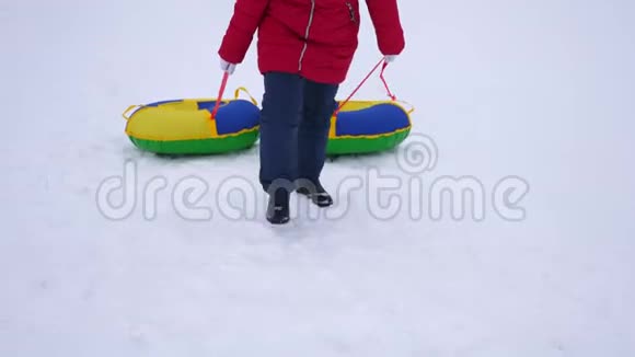 少女手持雪碟爬上雪山新鲜空气中的冬季游戏圣诞节视频的预览图