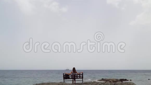 阿拉尼亚全景海景一个孤独的女孩坐在长凳上视频的预览图