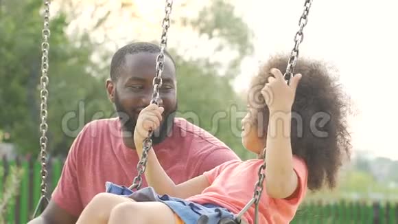 照顾非裔美国人的父亲和他的小女儿荡秋千家庭周末快乐视频的预览图