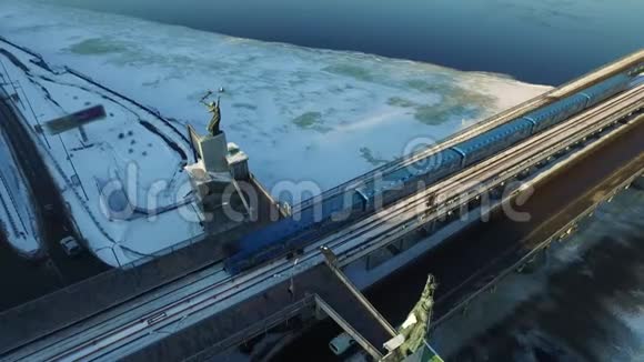 在冬季城市的结冰河上地铁列车在车桥上方行驶视频的预览图
