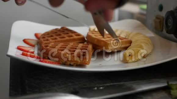 厨师一步一步准备比利时华夫饼包括香蕉草莓冰淇淋蜂蜜和巧克力糖浆视频的预览图