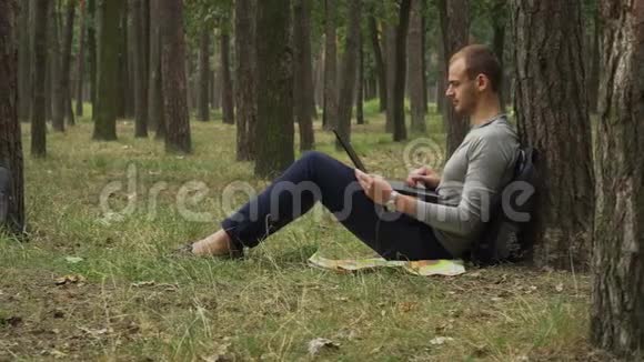 年轻人在森林里做笔记本电脑视频的预览图