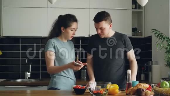 年轻卷毛的女人在丈夫做饭的时候他的手机上显示出一些令人不快的东西视频的预览图
