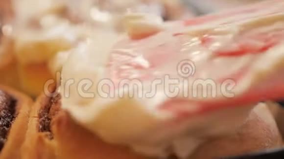 将白色奶油焦糖奶油涂在新鲜的热肉桂面包上加入香料以慢动作播放近4K视频视频的预览图