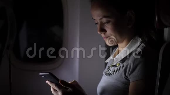 夜间靠窗坐飞机的智能手机女人视频的预览图