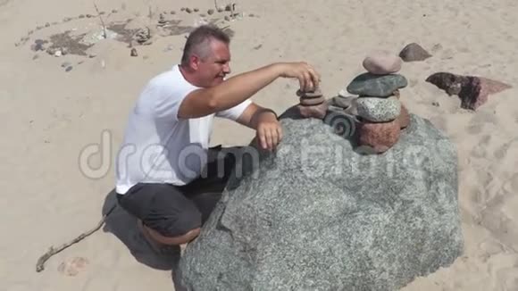 人类在海滩上建造了一座平衡的石头金字塔视频的预览图